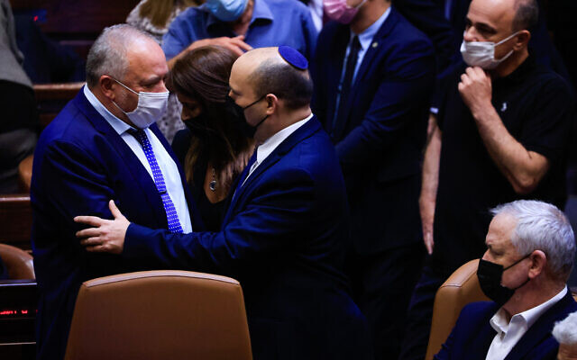 Finance Minister Avigdor Liberman, left, shakes hands with Prime Minister Naftali Bennett during a Knesset vote on the state budget, September 2, 2021 (Olivier Fitoussi/Flash90)